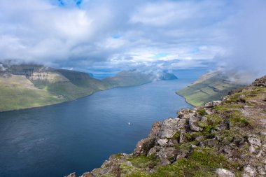 Okyanus manzaralı ve bulutlu gökyüzü olan dramatik kıyı manzarası. Bordoy Adası 'ndaki Klakkur Patikası' ndan görüntü. Faroe Adaları tatili.