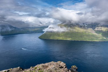 Okyanus manzaralı ve bulutlu gökyüzü olan dramatik kıyı manzarası. Bordoy Adası 'ndaki Klakkur Patikası' ndan görüntü. Faroe Adaları tatili.