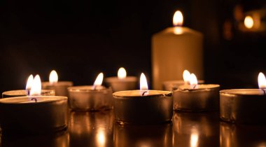 Geceleri mum yakmak. Sıcak ve rahat atmosferik ışık. Karanlıkta parlayan birden fazla yanan mum. Yumuşak, sıcak bir ışık huzurlu ve romantik bir akşam atmosferi yaratıyor. Rahatlama, maneviyat veya hafıza temaları için mükemmel..