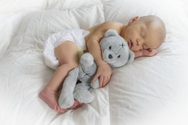 Uyuyan yeni doğmuş bebek Oyuncak ayıya sarılıyor.