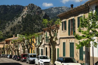 Bunyola 'da arka planda yüksek dağları olan bir sokak Mallorca' da güneşli bir bahar gününde açık mavi gökyüzü