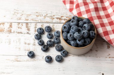 Kırmızı kareli masa örtüsü olan bir kasede taze yaban mersini..