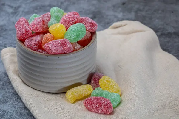 Renkli ekşi şekerler bir kase içinde kumaşla. 