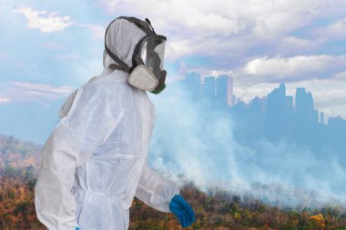 Beyaz koruma giysisi ve büyük şehirlerin gölgesi altında tam gaz maskesi giyen memurlar orman yangını dumanı ve küresel ısınmanın arka plandaki etkileri nedeniyle hava kirliliği riski altındalar..
