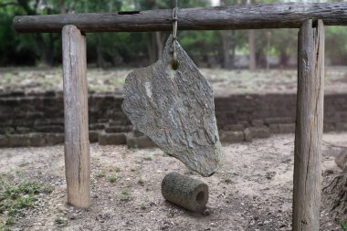 Dvaravati döneminden kalma taş çan Tayland 'da eski bir bölgede harabelerin önünde ahşap bir kirişe asılıydı..