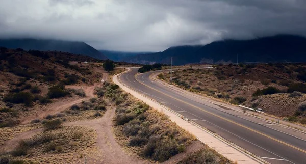 暗い曇り空の日に山を背景に砂漠を横断する道の壮大なショット — ストック写真