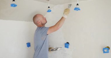 Adam eski duvara alçı yapıştırıp yeniliyor. Eski duvarları pürüzsüz alçıyla onarıyorum. DIY duvar yenileme: Eski duvarları sıvamak için pürüzsüz alçı profesyonel ipuçları uygulanıyor. Öğretici