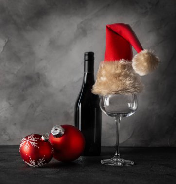 Bir şişe şarap, köknar dallarının arka planında Noel Baba şapkası olan bir bardak. Noel kompozisyonu.