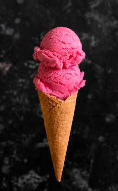 Koyu arkaplanda waffle külahında çilekli çilekli dondurma.