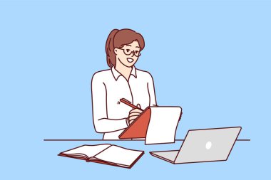 Başarılı bir iş kadını ya da internet üzerinden çalışan serbest çalışan bir kız, iş yerinde dizüstü bilgisayarla çalışıyor. Bir kadın not alıyor. Masanın yanında duruyor. Dizüstü bilgisayarının planlama günü. 