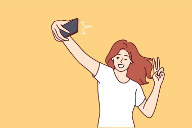 Kadın selfie çekerken gülüyor ve sosyal ağa ya da çöpçatanlık sitesine barış işareti koyuyor. Kız blogcu, aboneler için selfie videosu kaydederek jest yapıyor 