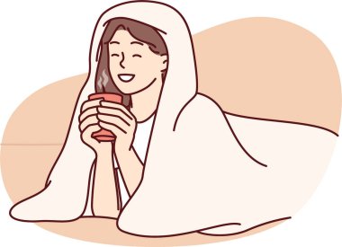 Battaniyeye sarılı bir fincan sıcak kahve ve kışın tadını çıkaran bir kız. Soğuk bir sokakta sonbahar havası yaratmak için yürüdükten sonra battaniyeyle sıcak içecek içen kadın.