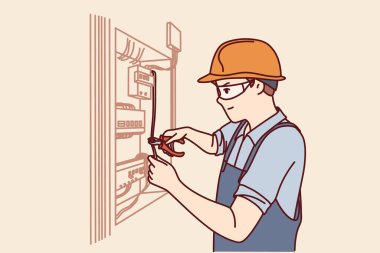 Elektrikçi adam güç kalkanını tamir eder ve konut binasını veya fabrikayı elektriğe bağlar. Elektrikçi üniformalı adam elektrik makineleri ve kabloları olan kabinin yanında duran elektrik tesisatını tamir ediyor.
