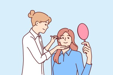 Kadın güzellik uzmanı, klinikte estetik tedavi gören aynalı bir hasta için makyaj yapıyor. Kız makyaj uzmanı film çekmeden ya da sahneye çıkmadan önce aktrisin yüzüne makyaj yapar.