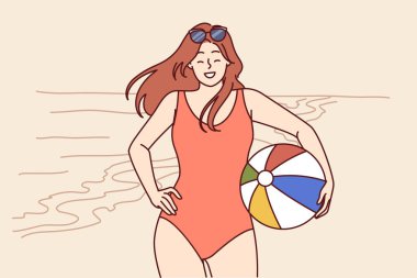 Plaj voleybolu için topu olan bikinili bir kadın tropik tatil beldesinde yaz tatilinin tadını çıkarıyor. Kız turist okyanus kıyısında poz verirken gülümser ve sizi ortak tura davet eder.