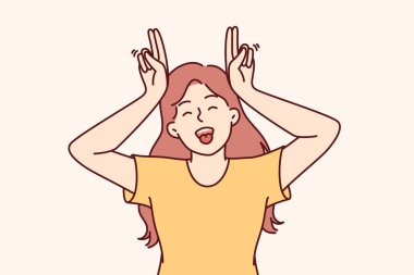 Küçük komik kız parmaklarından boynuz yapıyor ve dillerini gösteriyor, başkalarını ve arkadaşlarını neşelendirmek istiyor. Genç kız gülüyor, suratını ekşitiyor ve yetişkin olmayı reddediyor.