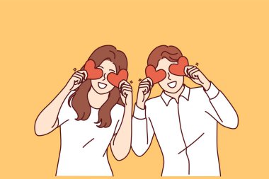 Romantik çift, sevgililer günü kartlarını gözlerinde kalp şeklinde tutarlar ve ekranda gülümserler. Beyaz elbiseli romantik erkek ve kız ruh eşinin varlığıyla seviniyor.