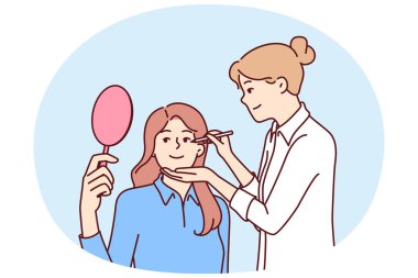 Kadın güzellik uzmanı, klinikte estetik tedavi gören aynalı bir hasta için makyaj yapıyor. Kız makyaj uzmanı film çekmeden ya da sahneye çıkmadan önce aktrisin yüzüne makyaj yapar.