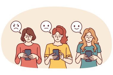 İnternet geribildirim konsepti için farklı yüz ifadeleri olan emojinin yanında telefonu olan kadınlar. Akıllı telefonlu kızlar mobil uygulama veya şirket web sitesine olumlu veya olumsuz geri bildirim bırakırlar