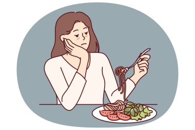 İştahsızlık çeken kadın iştahsızlıktan üzgün ve masada spagetti ve salatayla oturuyor. Zayıf görünümlü bir kız yanlış beslenmeden sonra iştahsızlıktan muzdarip.