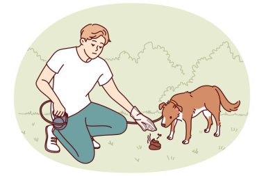 Köpeği gezdiren adam, parkı kirletmemek için dışkısını plastik torbaya koyar. Genç adam köpek sahibi köpek yavrusunun pisliğini temizlerken dikkatli davranıyor ve çevreyi temizliyor.
