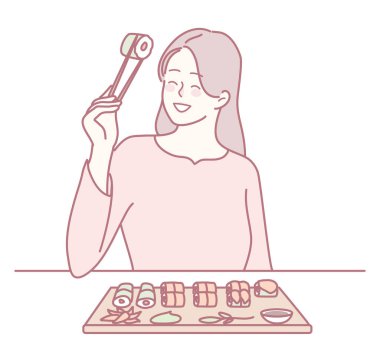 Bir kadın yemek çubuklarını güzel bir suşi tabağının üzerinde tutarak suşiye olan aşkını gösteriyor.