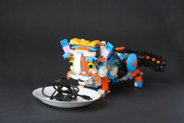 Robot kedi, elektronik yiyeceklerle dolu bir tabağa bakıyor.