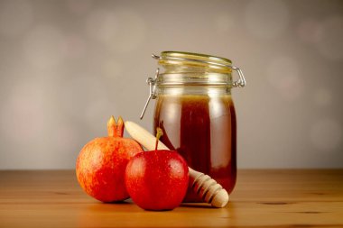 Kavanozda bal, ahşap masada elma ve nar.