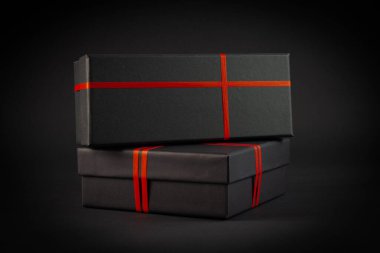 Siyah arka planda kırmızı kurdeleli siyah hediye kutusu. Hediye konsepti.