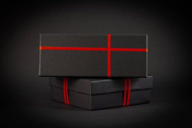 Siyah arka planda kırmızı kurdeleli siyah hediye kutusu. Hediye konsepti.