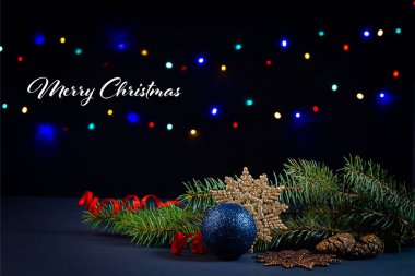 Noel ağacı, süslemeler, ışıklar ve siyah arka planda bir hediye kutusu.