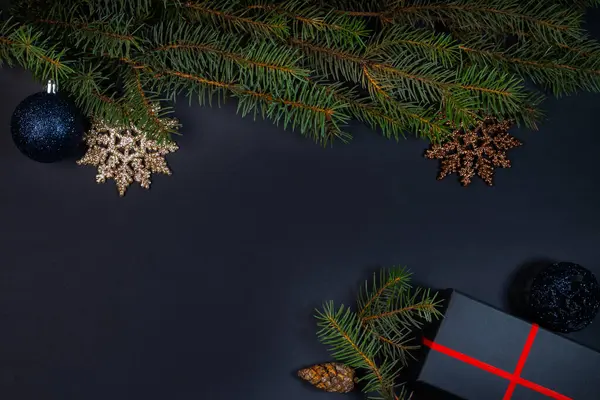  Bir Noel ağacı, süslemeler, ışıklar ve siyah arka planda bir hediye kutusu. Üst görünüm.