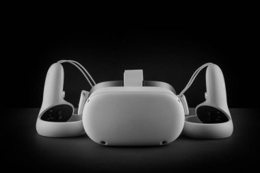 Siyah arka planda sanal gerçeklik kulaklığı. VR gözlükleri ve video oyun denetleyicileri.