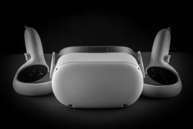 Siyah arka planda sanal gerçeklik kulaklığı. VR gözlükleri ve video oyun denetleyicileri.