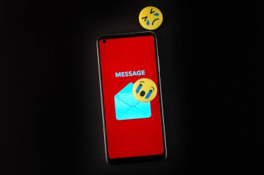 Siyah arka planda Emoji yüzü ve akıllı telefon. Duygusal kavram.