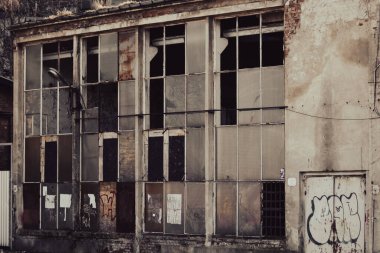 Kırık camları ve duvarında grafiti olan terk edilmiş bir fabrika binası.