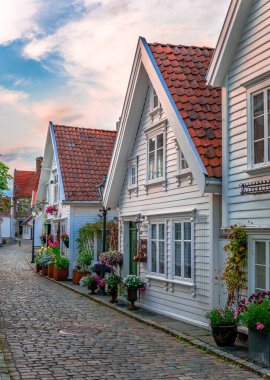 Stavanger, Norveç 'teki Old Town' daki Ovre Strandgate manzarası. Kırsal sokaklarda güzel çiçeklerle süslenmiş beyaz ahşap evler..