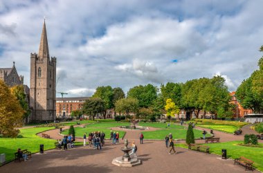 Dublin, İrlanda - 15 Eylül 2022: İnsanlar St. Patrick 's Park' ta güneşli bir günün tadını çıkarıyor. St. Patrick Katedrali solda..