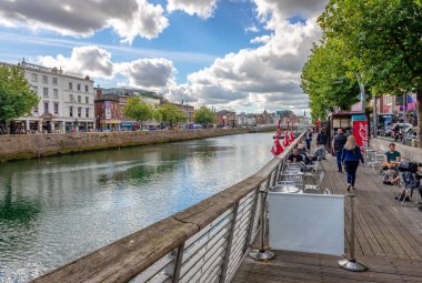 Dublin, İrlanda - 16 Eylül 2022: Liffey nehrinin kuzey kıyısında kaldırım kafeleri olan bir rıhtım. Arka planda Aston Quay ve Ha 'penny köprüsü var..