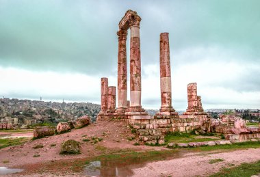 Arka planda, Ürdün 'ün başkenti Amman' ın bulunduğu Herkül Tapınağı 'nın kalıntıları. Bu tapınak Amman Kalesi 'ndeki en önemli Roma yapısıdır..