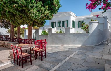 Yazın ağaçların gölgesinde masaları olan kaldırım kafesi. Pirgo köyü, Tinos Adası, Cyclades, Yunanistan