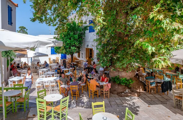 ギリシャのピラゴス 2023年9月22日 古い飛行機の木の影の下でリフレッシュを楽しんでいる人々との村のメイン広場 ピラゴスは キクラデス ティノス島の山岳村です ストックフォト