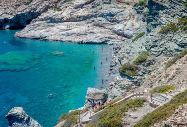 Yunanistan 'ın Amorgos kentindeki Mouros plajı - 25 Temmuz 2024: Mouros' un yüksek açılı manzarası, Vrutsi köyü yakınlarındaki inanılmaz bir çakıl taşı plajı. Plajın uzak ucundaki su altı mağaraları olan kristal berrak sular..