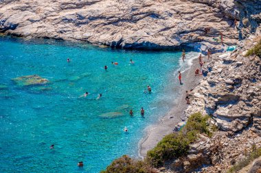Yunanistan 'ın Amorgos kentindeki Mouros plajı - 25 Temmuz 2024: Mouros' un yüksek açılı manzarası, Vrutsi köyü yakınlarındaki inanılmaz bir çakıl taşı plajı. Plajın uzak ucundaki su altı mağaraları olan kristal berrak sular..