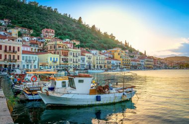 Gytheio, Greece - June 27 2024: The waterfront of the town, with fishing boats and neoclassical houses at the sunset. clipart