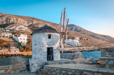 Aigiali, Greece - July 27 2024: The iconic old windmill that stands right next to the port. Aigiali is a picturesque fishing village in Amorgos Island, Cyclades, Greece. clipart