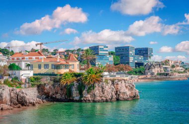 Old and modern residence facing the Atlantic ocean in Cascais, Portugal. Scenic landscape with rocky coast on a sunny day.