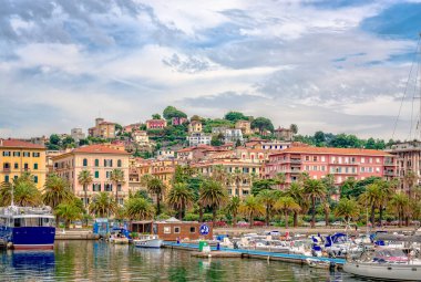 La Spezia, İtalya - 27 Mayıs 2018: Arka planda bir sürü tekne, palmiye ağaçları ve deniz kenarındaki evler ile denizden görünen liman manzarası.