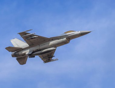 Falcon savaş uçağı mavi gökyüzünde yüksek hızda uçuyor. 