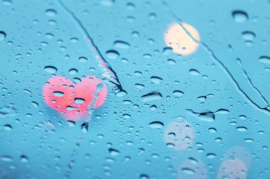 Close up raindrops on surface glasses car with lights traffic heart shape bokeh background clipart